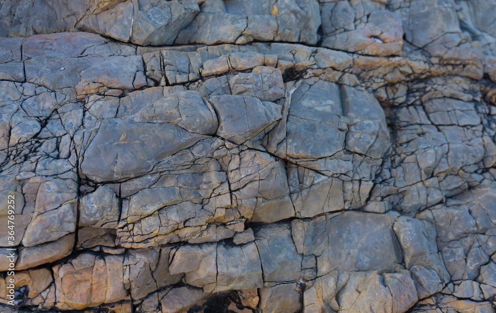 Cracked stone texture. Cold blue, grey, and yellow colors. Nature stone background. Cliff pattern.