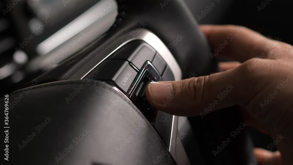Driver of a vehicle using the switch and buttons of the car steering wheel to adjust settings while driving on the road. Driver of a vehicle using the switch and buttons of the car steering wheel to adjust settings while driving on the road.