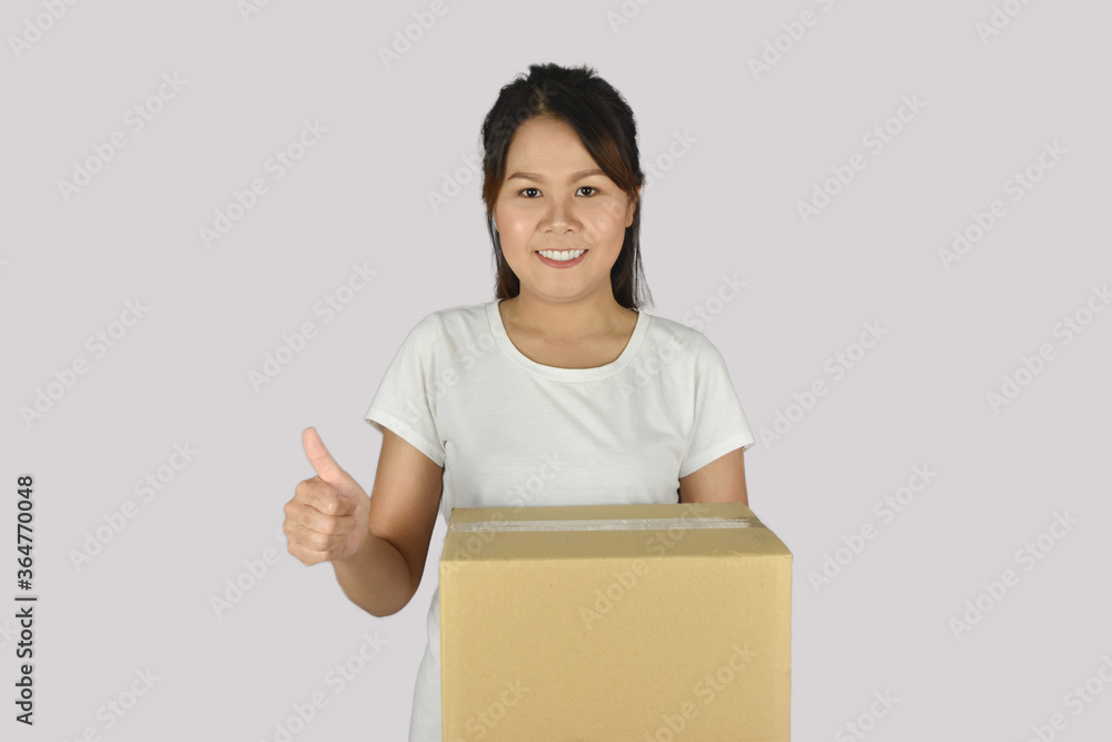 Woman wearing white shirt, holding a box with showing thumbs up. Woman wearing white shirt, holding a box with showing thumbs up.