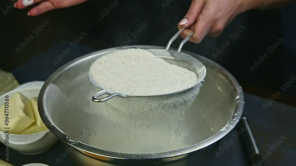 slow motion closeup woman hands sifting flour by metal sieve into empty steel bowl slow motion closeup woman hands sifting flour by metal sieve into empty steel bowl