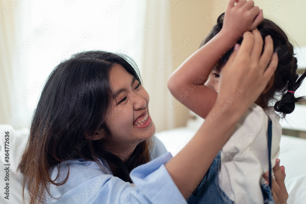 Happy Asian family loving children, kid hugging her sister, relaxing together in bed Happy Asian family loving children, kid hugging her sister, relaxing together in bed