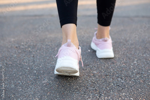 Closeup on running shoes of woman on the running road.