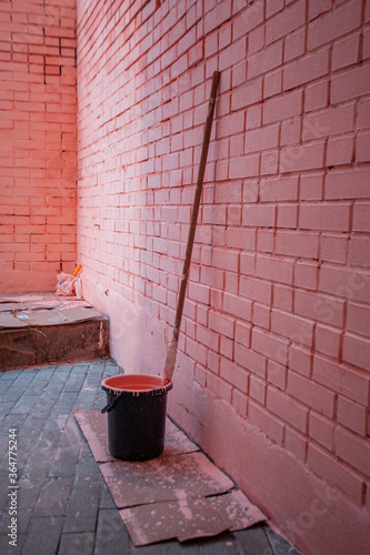 Pink brick wall. Paint roller for painting walls. Black bucket with paint. Repairs. High quality photo © VKari