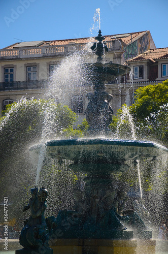 Fountain in the Rossio Square or Pedro IV Square (Praça de D. Pedro IV) with buildings in the background, in Lisbon, Portugal.