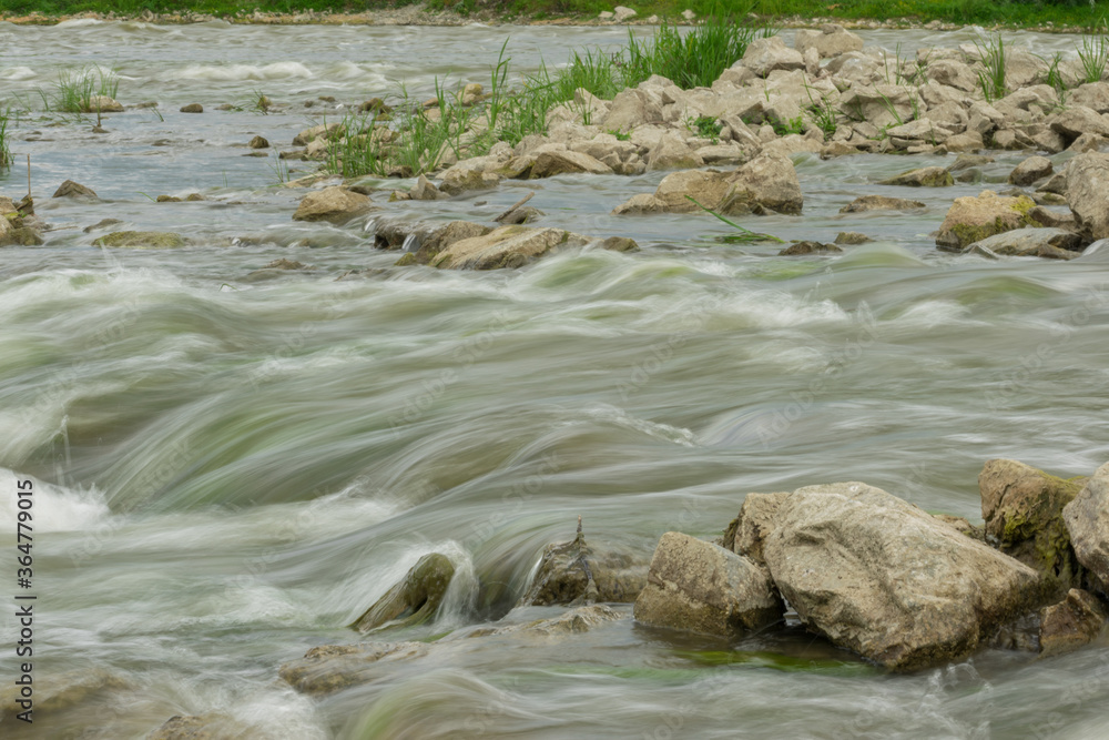 The flow of the river in the summer forest. Stones washed by water. Reflection on the water. water movement for a long exposure. The flow of the river in the summer forest. Stones washed by water. Reflection on the water. water movement for a long exposure.
