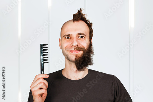 Man with half shaved hair head. holding comb Guy before and after transplant and alopecia.