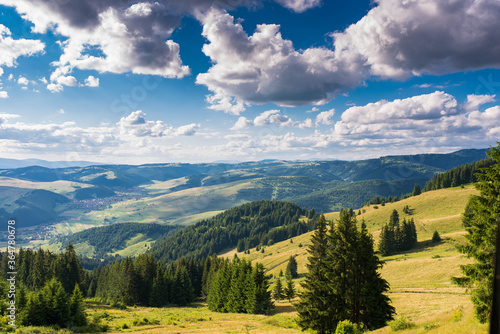View from the top of the mountain at summertime  blue sky with white clouds  hungarian villages in the valley in Transylvania  Romania.