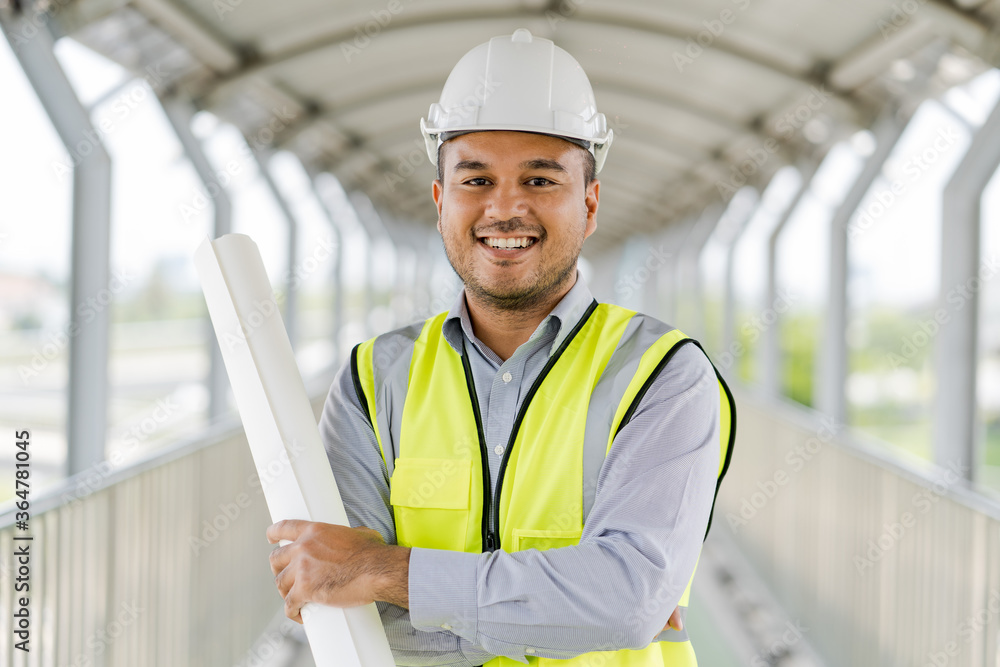Portrait engineer handsome man or architect looking construction with blueprint and white safety helme in construction site. Portrait engineer handsome man or architect looking construction with blueprint and white safety helme in construction site.