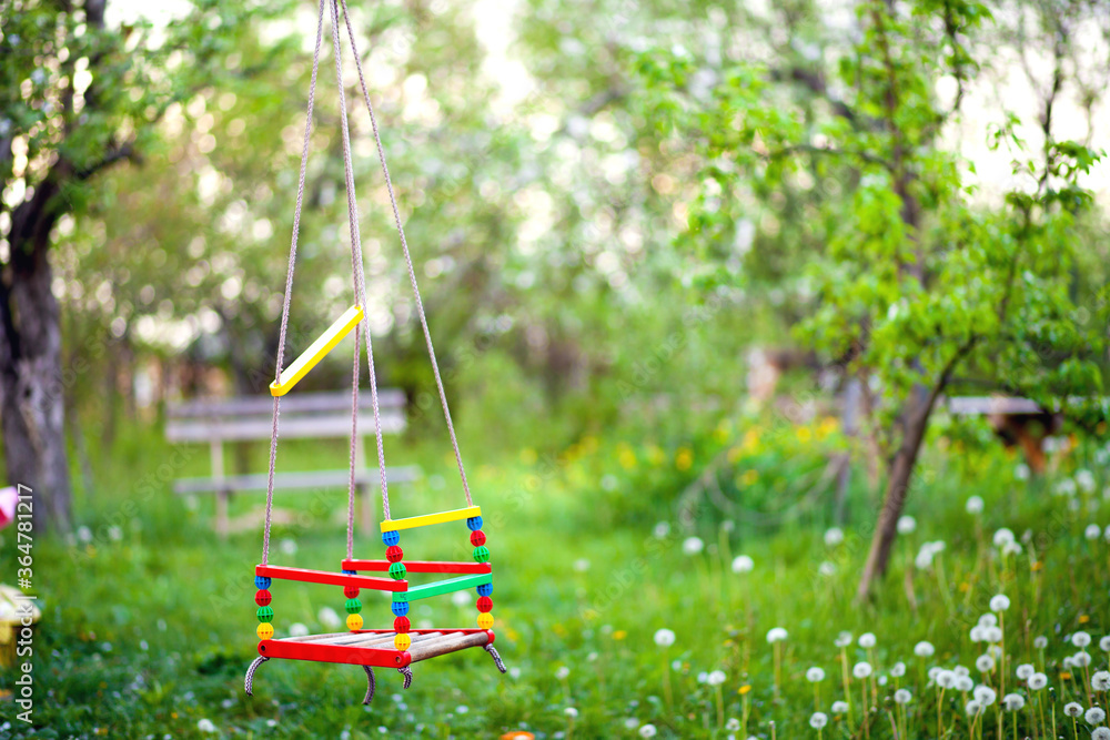 Empty rope for a children's swing hanging on a tree in the garden in the evening in summer Empty rope for a children's swing hanging on a tree in the garden in the evening in summer