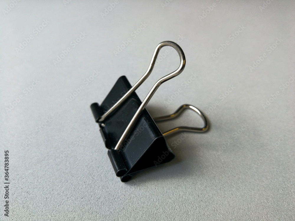 Fototapeta premium Flexible steel office paper clip, placed on a gray background