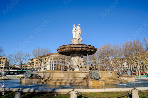 The Fountain of the Rotunda in the morning sun. Beautiful sunny day in Aix-en-Provence. A large uniformly blue sky illuminates the city. The white marble of the statues stands out in the sky.