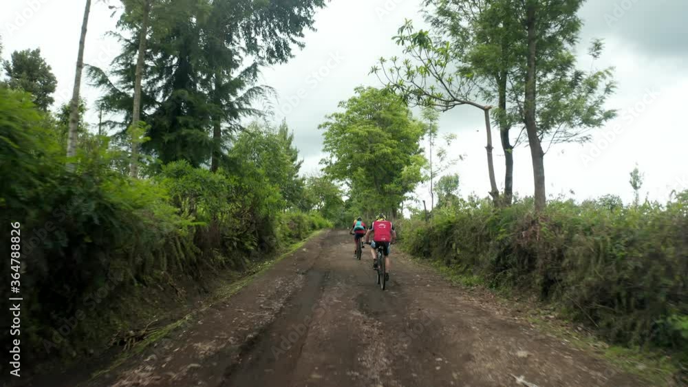 Marathon athletes cycling on a dirt road with mountain bike riding uphill very heavy workout in jungle forest Tanzania - 4k Marathon athletes cycling on a dirt road with mountain bike riding uphill very heavy workout in jungle forest Tanzania - 4k