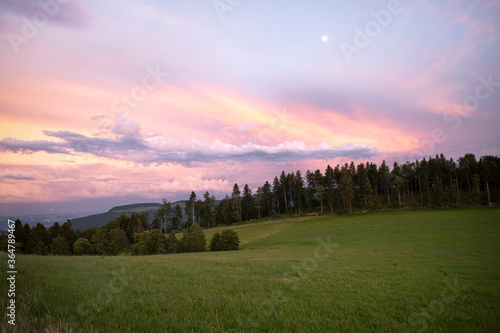 Outstanding evening sky, with magical purple and pink clouds. Countryside dusk landscape, swiss mountains.