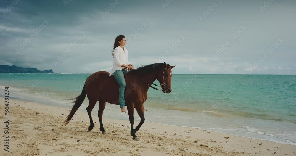 Woman horseback riding at the beach at sunrise on beautiful brown horse, cinematic slow motion Woman horseback riding at the beach at sunrise on beautiful brown horse, cinematic slow motion