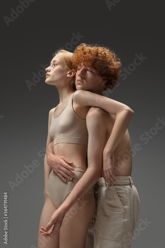 Catch me. Fashion portrait of beautiful redhead couple isolated on grey studio background. Concept of beauty, skin care, fashion and style. Artwork, modern and trendy portrait. Attractive model.