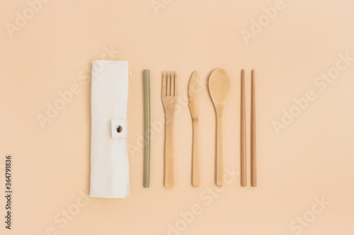 Kit of bamboo cutlery with a textile case on a beige background. Zero waste concept.