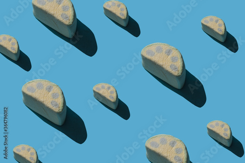 Pattern of tasty marshmallows with hard shadows on a blue background.