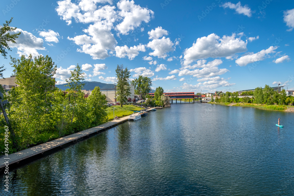 View of a paddle boarder on the Sand Creek River and Cedar St Bridge off Lake Pend Oreille in the downtown area of Sandpoint, Idaho, in the Inland Northwest, USA View of a paddle boarder on the Sand Creek River and Cedar St Bridge off Lake Pend Oreille in the downtown area of Sandpoint, Idaho, in the Inland Northwest, USA