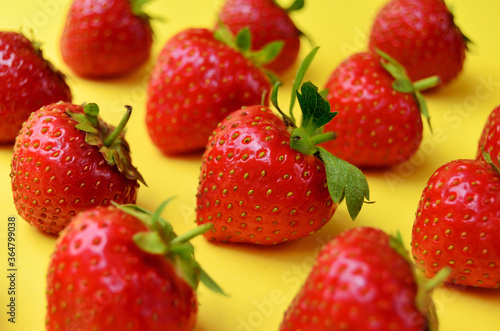 Strawberry red ripe sweet lined up diagonally for background on yellow close-up