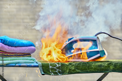 Iron for clothes caught fire on an ironing board. photo