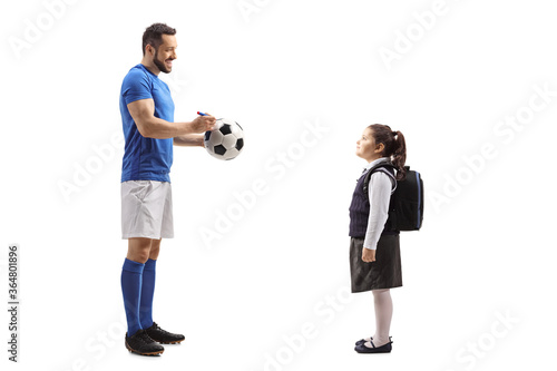 Footballer giving an autograph on a soccer ball to a schoolgirl