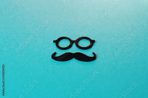 Glasses and mustache on a dark turquoise background. Male concept or card for father's day.