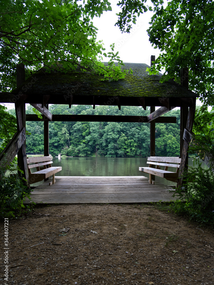 A shed by a lake with benches for people to sit on