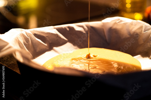 Pouring the raw dough from a homemade cake into a bowl to put it in the oven. Prepare a homemade cake at home at night in the kitchen with warm light.