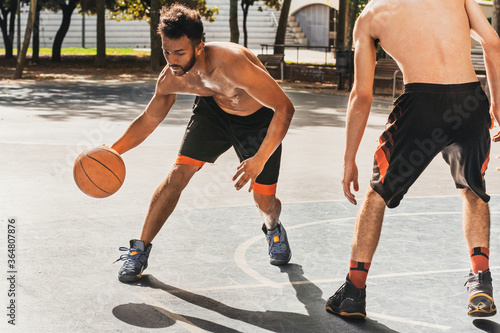 young man playing basketball dribbles his opponent