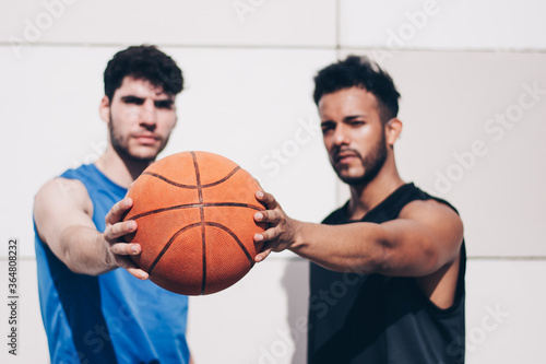 two basketball players of different races hold a ball together