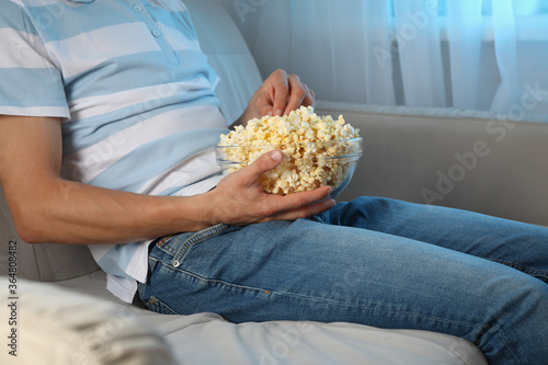 Man watching film on sofa and eat popcorn. Food for watching films
