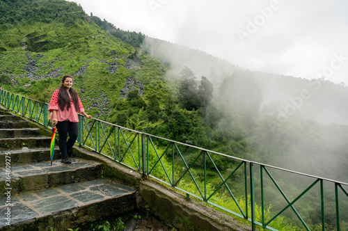 Young indian girl in a red dress standing on a series of stairs leading to the bhagsu falls in McLeodganj in himachal india