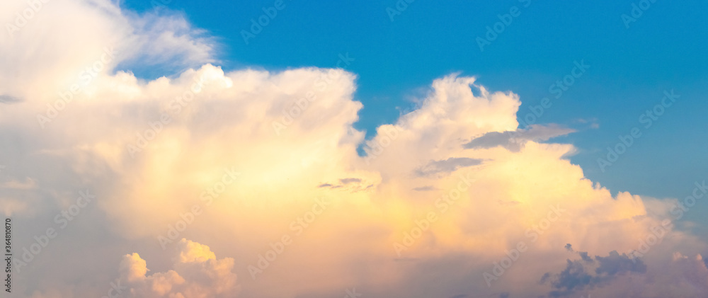 Fluffy clouds in the blue sky at sunset
