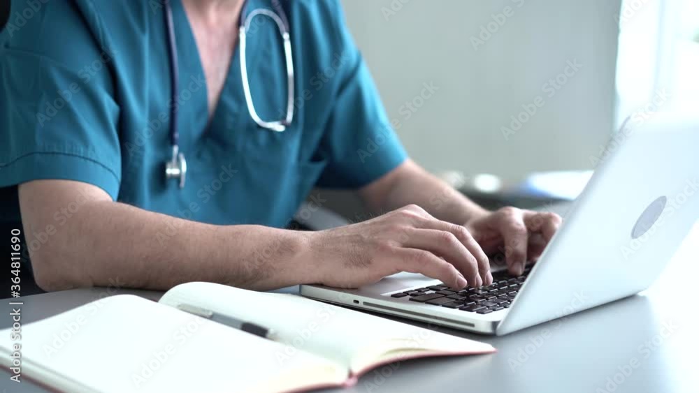 Qualified serious male therapist doing online research, reading news, making notes in medical journal. Focused old doctor physician using laptop at office desk. Qualified serious male therapist doing online research, reading news, making notes in medical journal. Focused old doctor physician using laptop at office desk.
