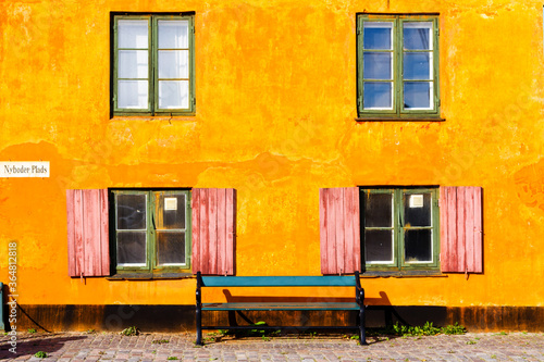 COPENHAGEN, DENMARK - OCTOBER 8, 2016: Nice old yellow houses of Nyboder, medieval district of Copenhagen, Denmark. Retro bicycled parked in front of the building on a pavement.