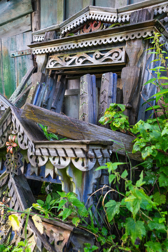 Old Russian Windows with carved wooden frames and colored elements lie near the fence  overgrown with grass.
