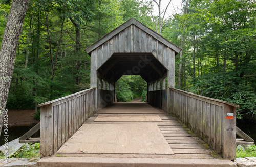 Wooden Covered bridge over a small river in a lush green forest at Devil's Hopyard State Park