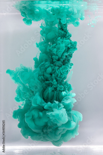 Green color drop in water, photo in motion. Ink swirling in fluid.