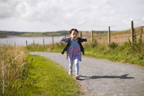 toddler girl running on the summer countryside road
