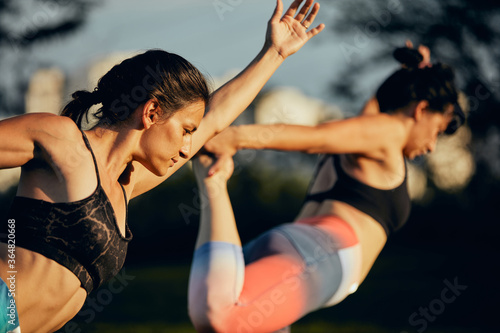 Two attractive women practicing yoga outdoors on a beautiful sunny day.