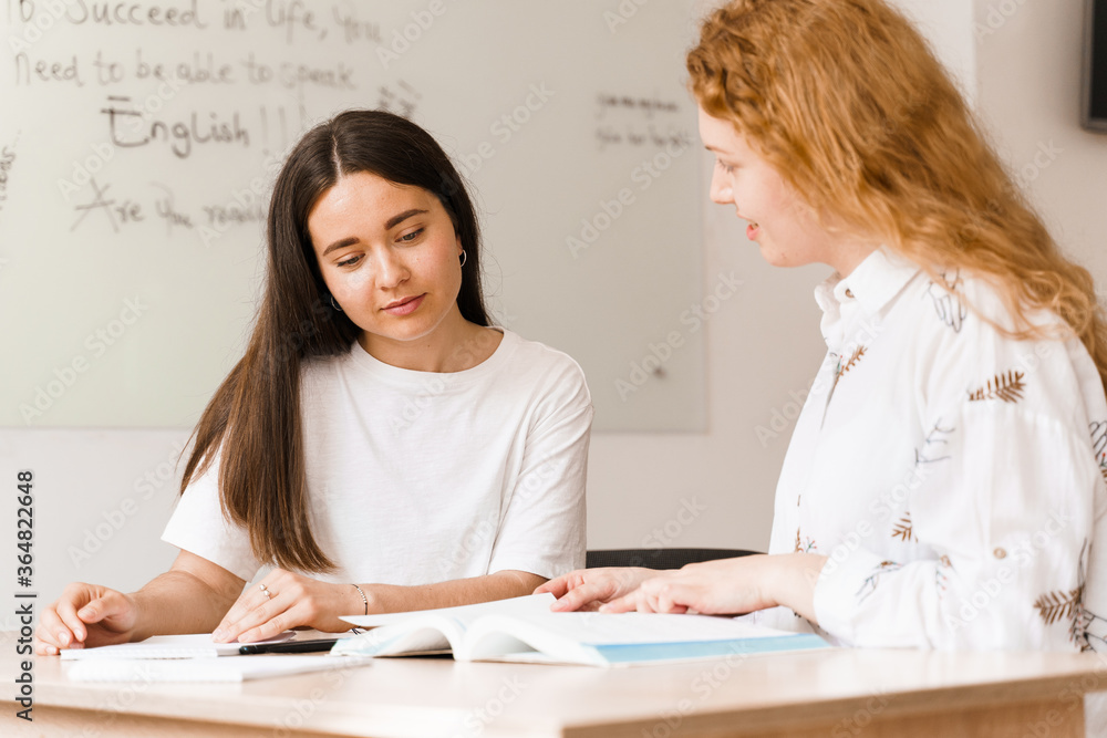 Teacher of english asks student in white class. 2 girls student answers to teacher. Working in group. Study english and british language. Teacher of english asks student in white class. 2 girls student answers to teacher. Working in group. Study english and british language.