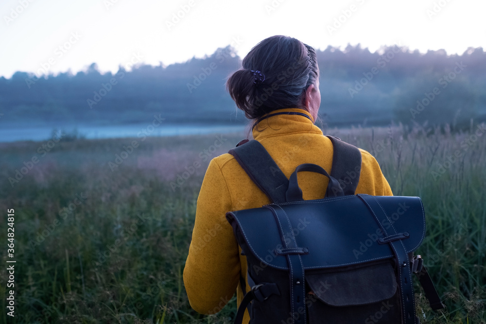 Caucasian woman walking through the meadow. Hiking early at the morning