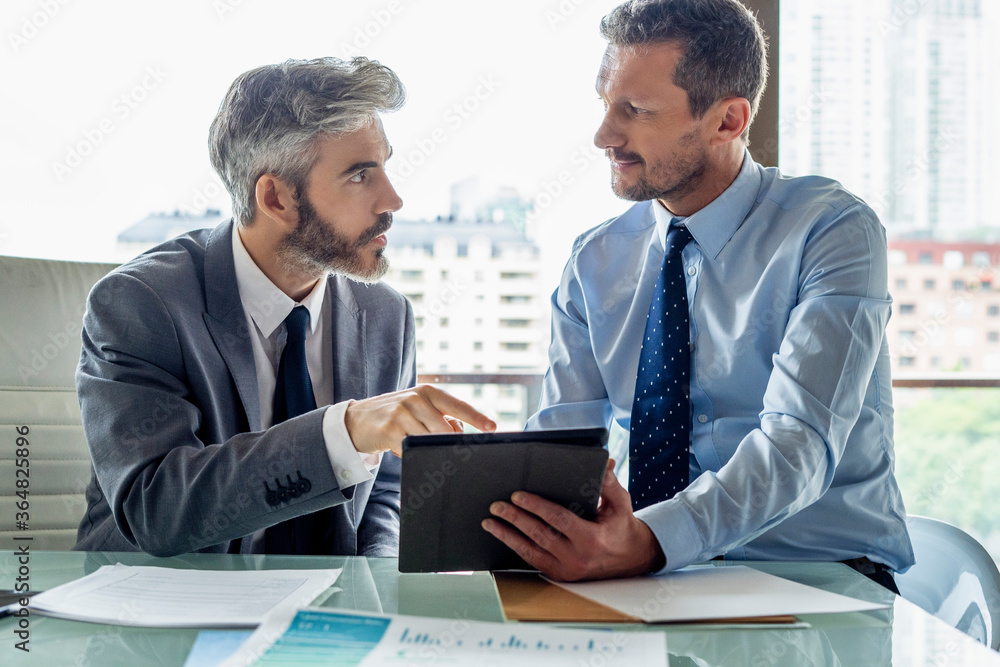 Businessmen discussing over digital tablet Businessmen discussing over digital tablet
