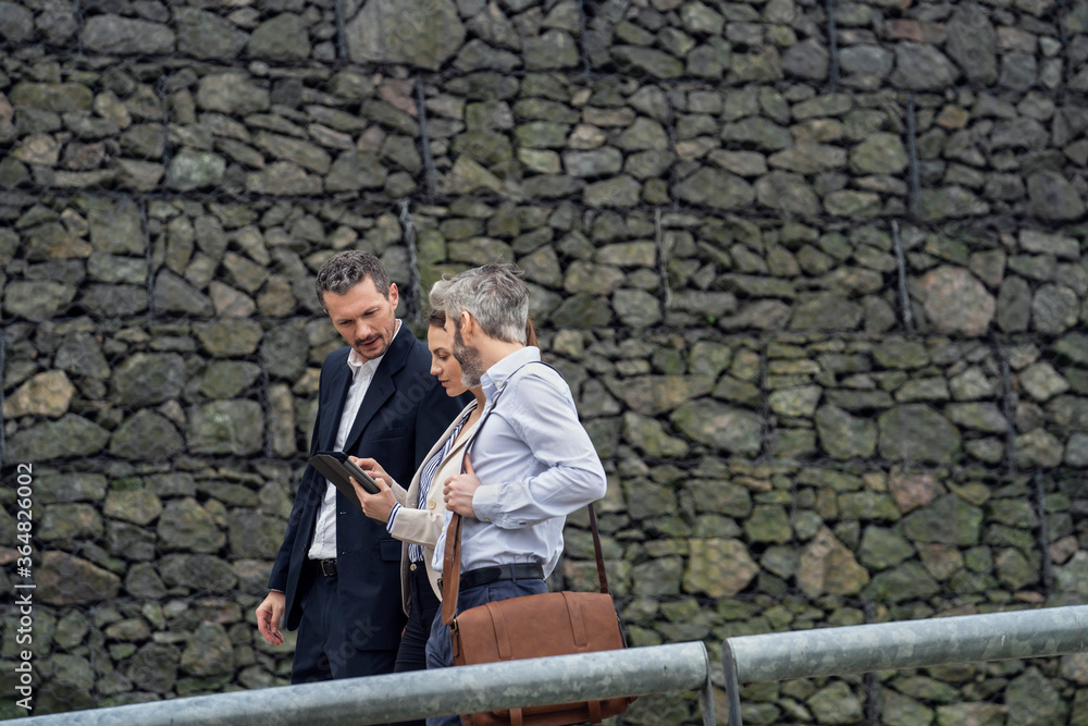 Businesspeople using digital tablet in public park Businesspeople using digital tablet in public park