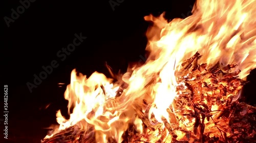 Fire at night outdoors, a pile of dry wood and leaves burn in flames. Fire burning in a campfire at night