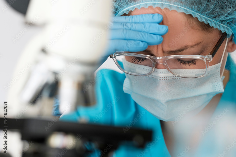 Healthcare professional with face mask using microscope Healthcare professional with face mask using microscope