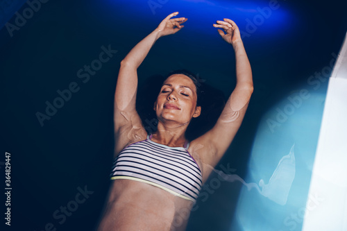 Quadro su tela Beautiful pregnant woman floating in tank filled with dense salt water used in meditation, therapy, and alternative medicine