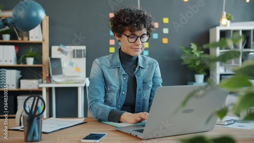 Slow motion of young successful businesswoman working with laptop computer in creative office focused on job. People and modern business concept.