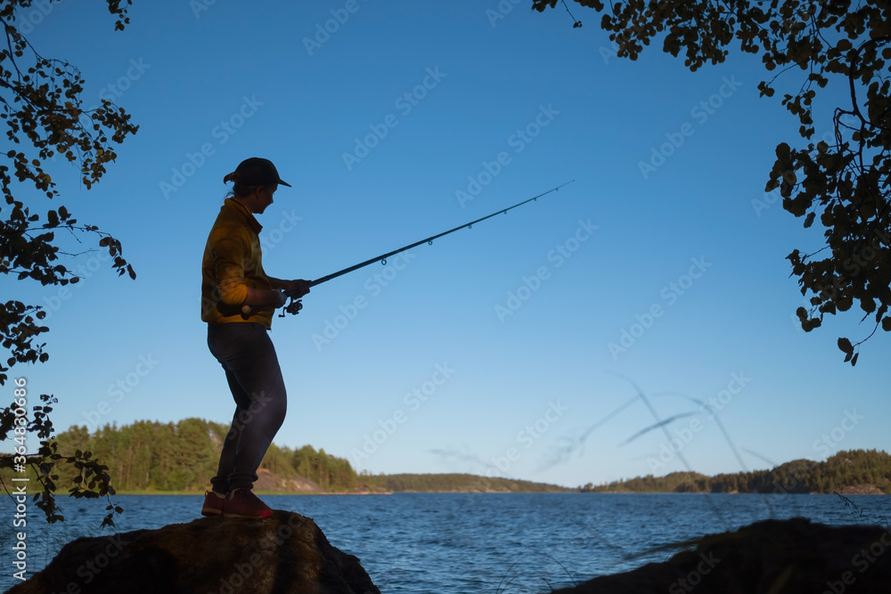 Silhouette of woman fishing on the lake on summer day Silhouette of woman fishing on the lake on summer day