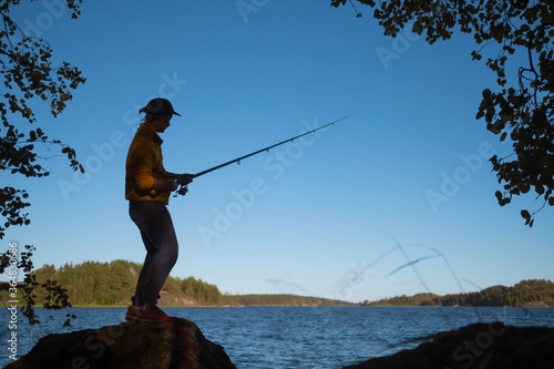 Silhouette of woman fishing on the lake on summer day